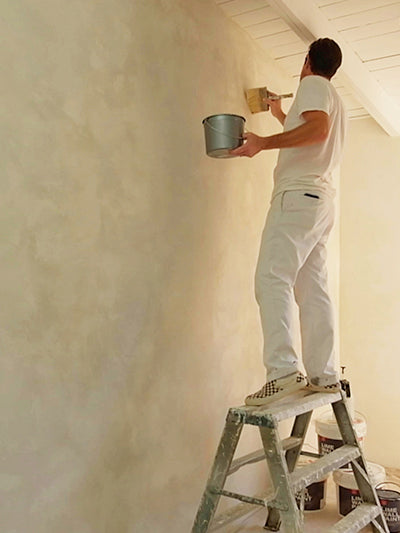 Jeremy Harnish using limewash paint on a wall showing technique