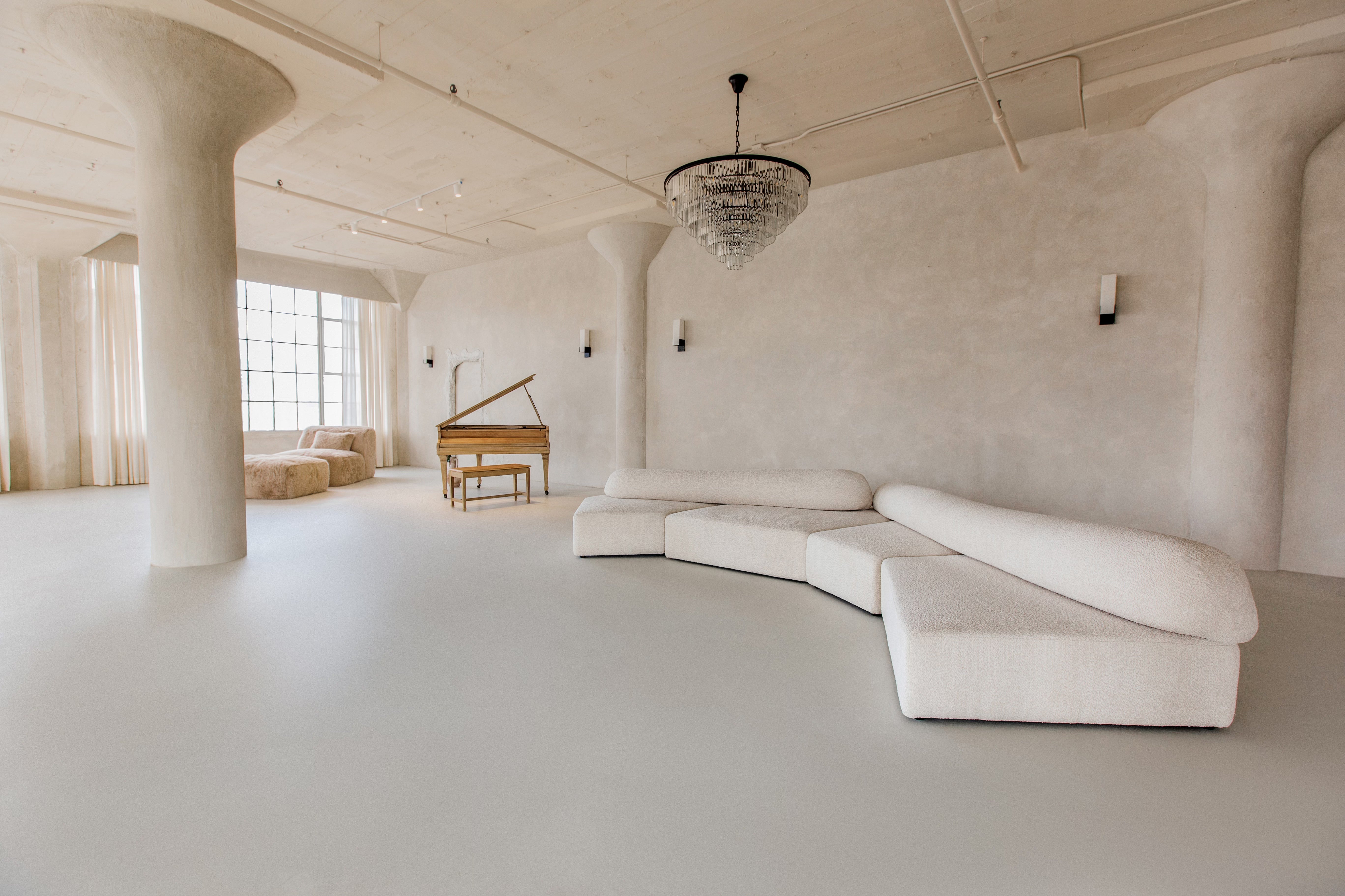 Huge open living room with a piano and chandelier. Textured walls painted using limewash wall paints